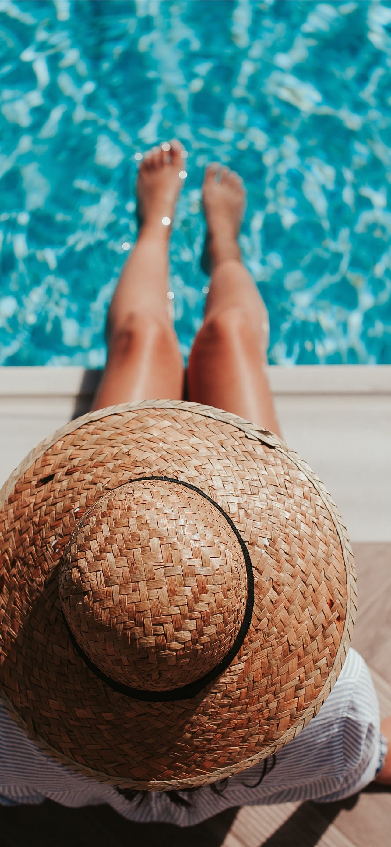 Woman Sitting On Poolside Setting Both Of Her Feet